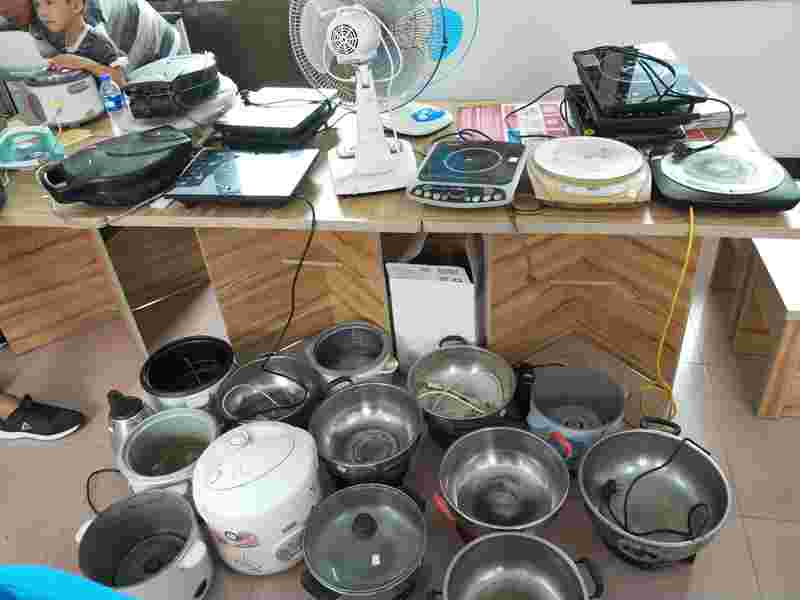 屋里堆满了大大小小的锅、电磁炉、电风扇